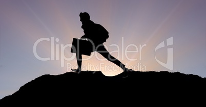 Silhouette businessman running on mountain during dusk