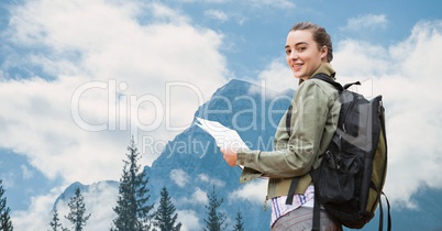 Female traveler holding maps against mountain