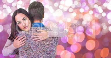 Portrait of young woman embracing man over bokeh