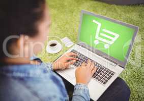 Woman using laptop with Shopping trolley icon