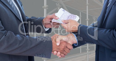 Midsection of business people shaking hands while passing money