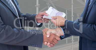 Midsection of business people shaking hands while passing money