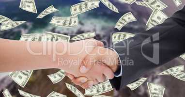 Close-up of business people shaking hands with money in background