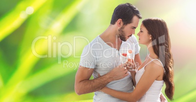 Passionate couple holding champagne flutes while embracing over blur background