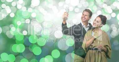 Happy couple holding champagne flutes over bokeh