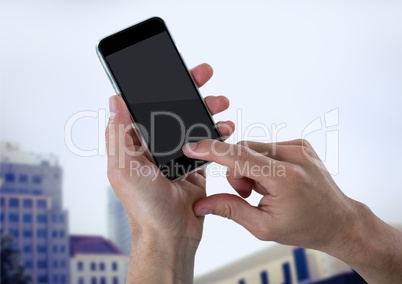 Hand with phone against blurry buildings