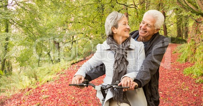 Loving senior couple riding bicycle in forest