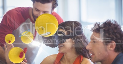 Happy businesswoman looking at emojis on VR glasses by colleagues