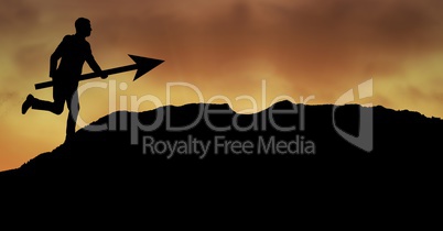 Businessman running with arrow on mountain during sunset