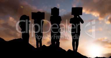 Silhouette children with books against sky during sunset