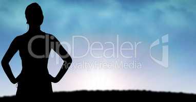 Silhouette sporty woman standing hands on hips on field during sunset