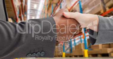 Male and female business partners shaking hands in warehouse