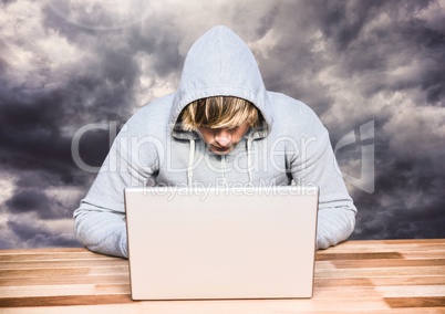 Criminal in hood on laptop in front of clouds