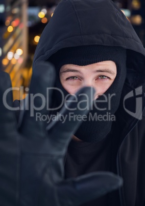 Criminal in hood in front of night city