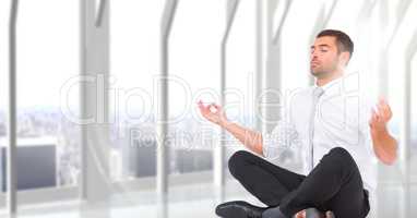 Business man meditating with flare against blurry white window