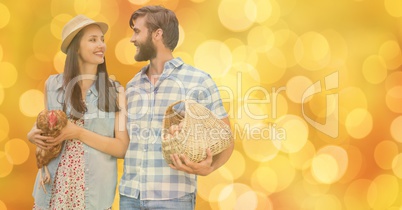 Happy couple with eggs and hen over bokeh