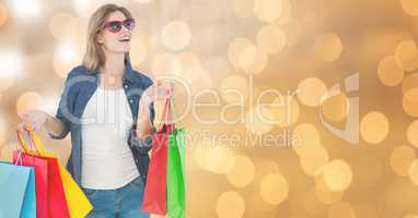 Surprised woman wearing sunglasses while holding shopping bags over bokeh