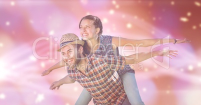 Man with with arms outstretched carrying woman on back against blur background