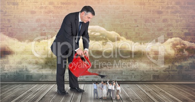 Digital composite image of businessman pouring water on employees from watering can
