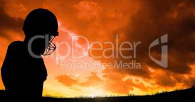Silhouette player wearing sport helmet against cloudy sky during sunset