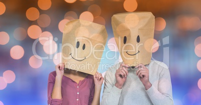 Couple covering faces with paper bags with smiles drawn on it