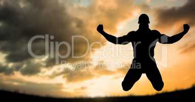 Silhouette muscular man in midair against sky during sunset