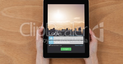 Hands holding digital tablet with log in page displayed on screen
