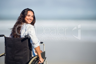 Portrait of woman sitting on wheelchair at beach
