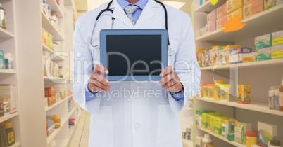 Midsection of doctor holding tablet computer while standing in pharmacy store