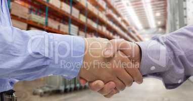 Close-up of business people shaking hands in warehouse