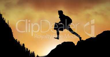 Silhouette businessman jumping on mountain against sky
