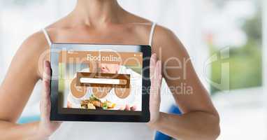 Midsection of woman holding digital tablet with food online page