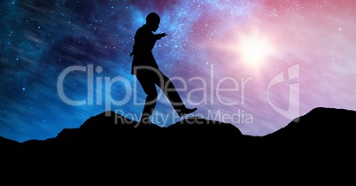 Silhouette businessman balancing on mountain against sky at night