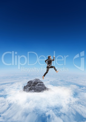 Business man jumping off mountain peak in the clouds