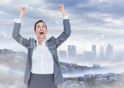 Business woman cheering on mountain against misty skyline