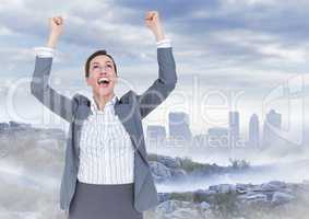 Business woman cheering on mountain against misty skyline