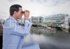 Business man with bionoculars against water across from blurry buildings