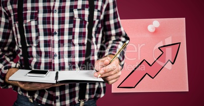 Man mid section with notebook against maroon background with pink sticky note and arrow