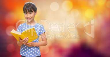 Smiling girl holding book over bokeh