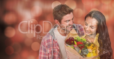 Happy man looking at woman with flowers over bokeh