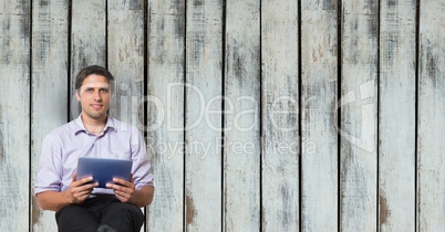 Businessman holding digital tablet against wooden wall