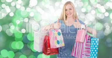 Female showing thumbs up while carrying colorful shopping bags