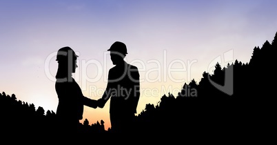 Silhouette business people shaking hands on mountain during sunset