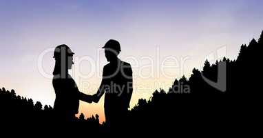 Silhouette business people shaking hands on mountain during sunset