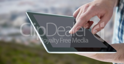 Hand with tablet against blurry skyline
