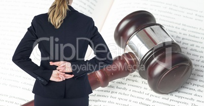 Midsection rear view of businesswoman with fingers crossed standing in front of gavel and law book