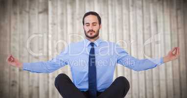 Business man meditating against blurry wood panel