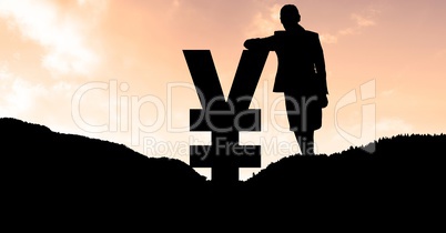 Silhouette businesswoman leaning on yen symbol on mountain during sunset