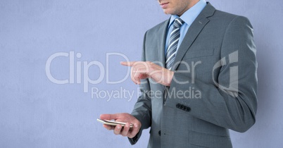 Midsection of businessman holding mobile phone while gesturing over purple background