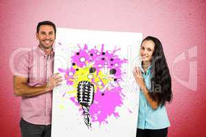 Portrait of smiling couple holding billboard with various icons against pink wall